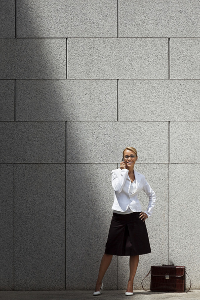 atrakcyjna kobieta mówiąc na telefon w pobliżu budynek biurowy - Zdjęcie, obraz