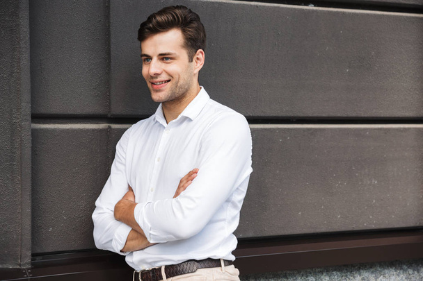 Confident young male manager formal dressed leaning on a wall outdoors - Foto, Bild
