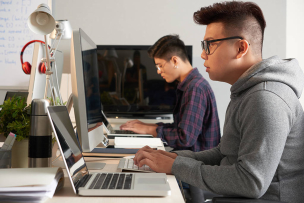 Asiatische Kollegen sitzen vor Computern und arbeiten  - Foto, Bild