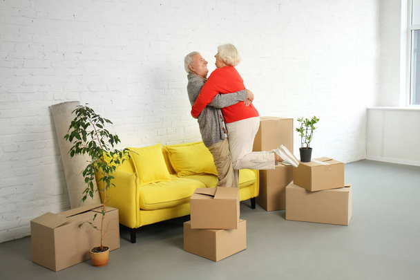 Feliz pareja madura con cajas después de mudarse a casa nueva
 - Foto, Imagen