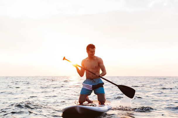 Image of young handsome man kayaking on lake sea. - Фото, зображення