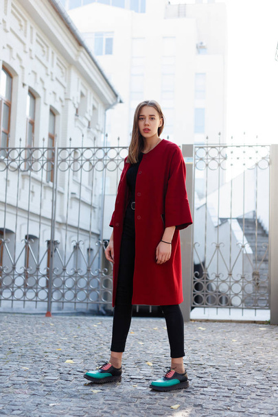 赤いコート、秋のファッショントレンドの街で歩いているスタイリッシュな美しい女性。ファッションの秋の写真。女性のファッション。都市生活. - 写真・画像
