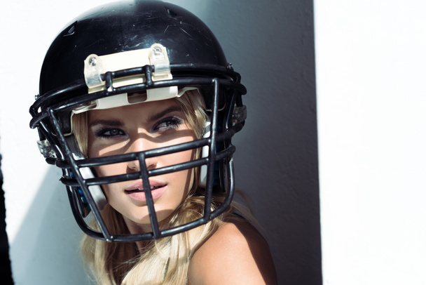 Nahaufnahme Porträt einer jungen Frau in Sport-BH und American-Football-Helm auf weiß - Foto, Bild