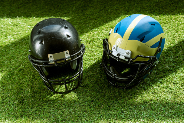 vista de ángulo alto de los cascos de seguridad de fútbol americano sobre hierba verde
 - Foto, Imagen