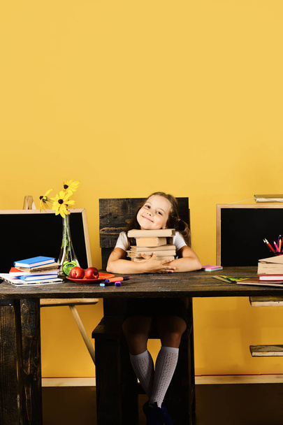 Girl sits at desk with colorful stationery, flowers and fruit - Φωτογραφία, εικόνα