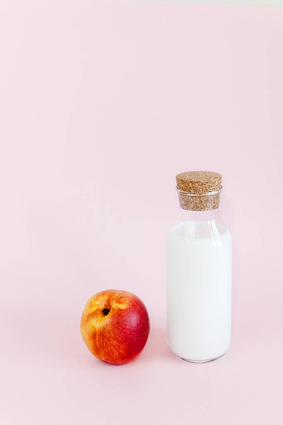Bottle milk with peach on pink background - Fotoğraf, Görsel