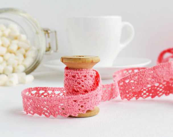 Pink cotton lace and wooden vintage spool on the white - Valokuva, kuva