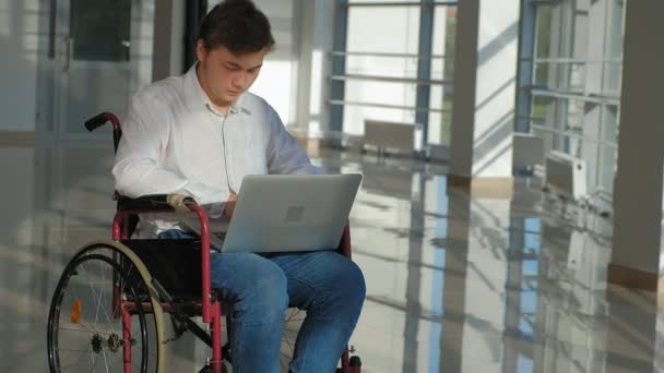 handicap zakenman op een rolstoel in een venster met een laptop - Video