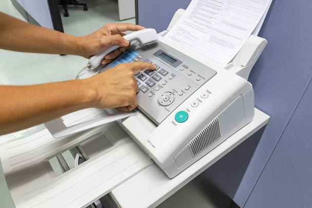 Hand Man zijn met behulp van een faxmachine in het kantoor. Bedrijfsconcept  - Foto, afbeelding