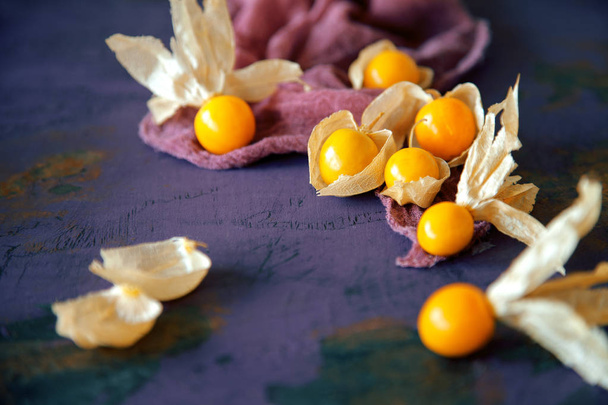 juicy ripe, yellow physalis on rustic wooden board with cloth, can be used as background - Photo, image
