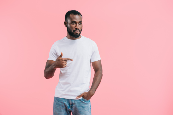 portrait of young african american man pointing away isolated on pink  - Foto, afbeelding