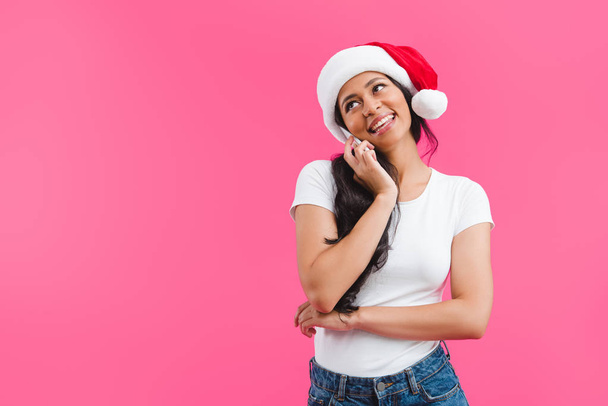 portrait of african american woman in santa claus hat talking on smartphone isolated on pink  - Photo, Image