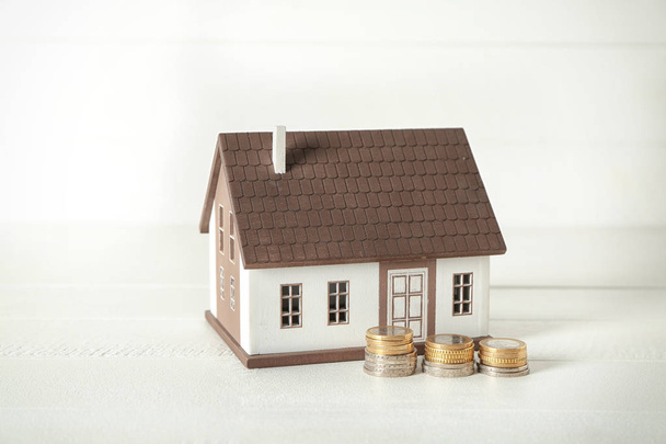 House model and coins on white table. Mortgage concept - 写真・画像