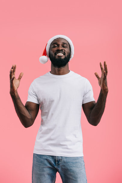 excité homme afro-américain avec les bras levés dans le chapeau de Noël isolé sur fond rose
 - Photo, image