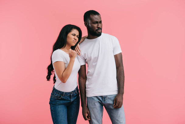 jeune femme afro-américaine agressive montrant poing tandis que son petit ami debout près isolé sur fond rose
  - Photo, image
