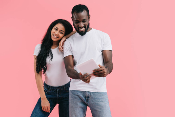 young african american couple using digital tablet isolated on pink background  - Fotó, kép