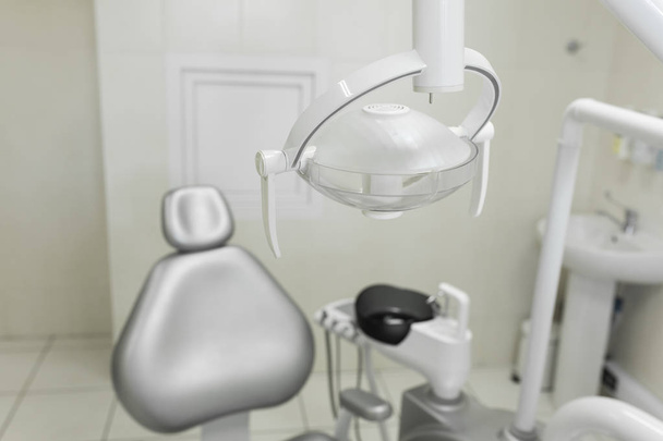 Moderni, hyvin varustettu hammaslääkärin toimisto, potilaan harmaa tuoli. Hampaiden porauskoneet ja muut hammaslääkintälaitteet. - Valokuva, kuva