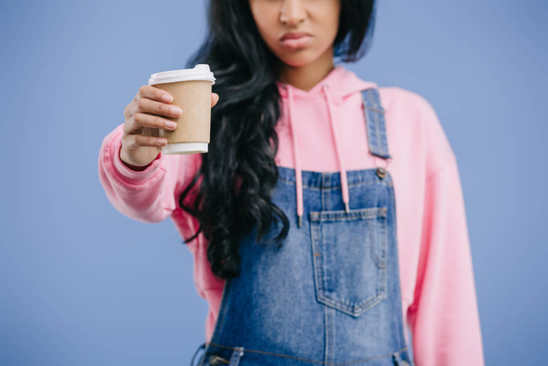 partial view of young african american woman showing disposable coffee cup isolated on blue background  - Foto, imagen