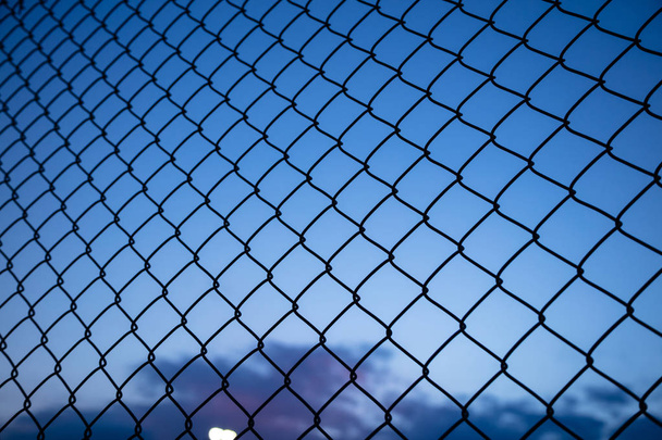 Cielo azul oscuro a través de valla de malla de alambre. Fondo desenfoque, vista de cerca de la jaula de enlace, fondo de pantalla
. - Foto, Imagen