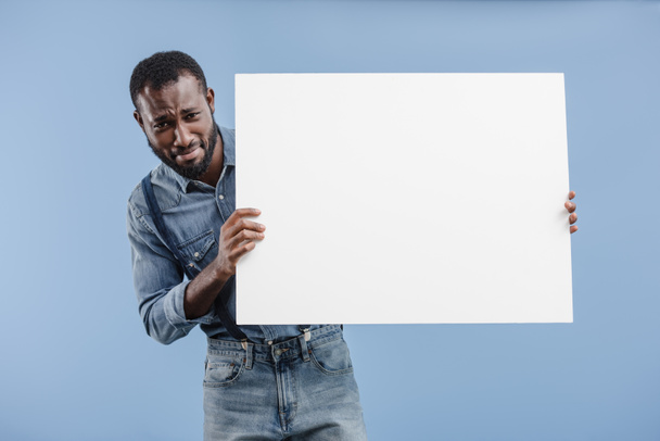 sad african american man holding blank placard isolated on blue - Фото, зображення
