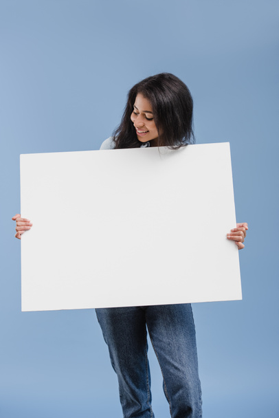 feliz atractivo afroamericano chica mirando en blanco cartel aislado en azul
 - Foto, imagen