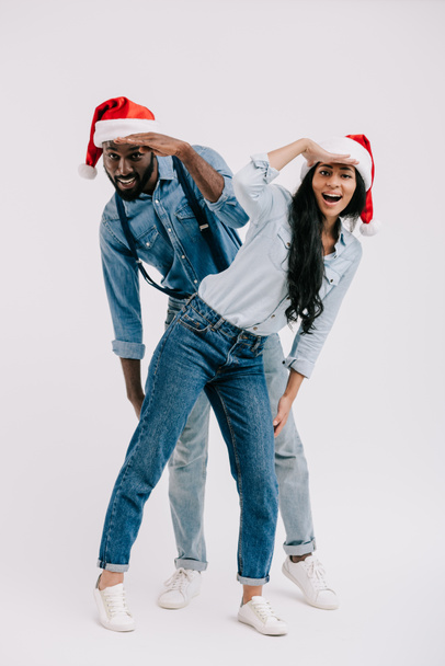 african american couple in santa hats having fun and looking for something isolated on white - Photo, Image