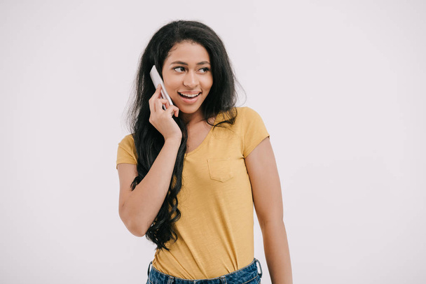sonriente atractiva afroamericana chica hablando por teléfono inteligente y mirando hacia otro lado aislado en blanco
 - Foto, imagen