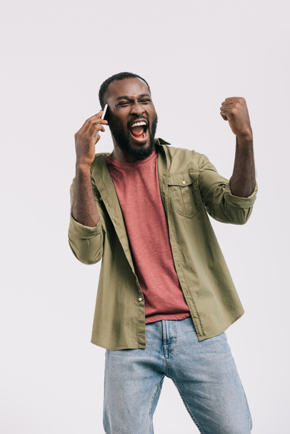 excited african american man talking by smartphone and showing yes gesture isolated on white - Φωτογραφία, εικόνα