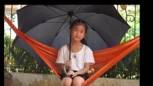 Dzieci pod parasolem na hamaku, kiedy pada deszcz. - Materiał filmowy, wideo