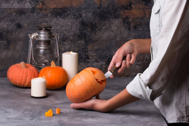 Woman carving little orange pumpkin into jack-o-lantern - Zdjęcie, obraz