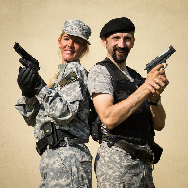 Usmívající se ženské a mužské vojáky ve vojenské uniformě, které jsou homologní s pistolemi v rukou. - Fotografie, Obrázek