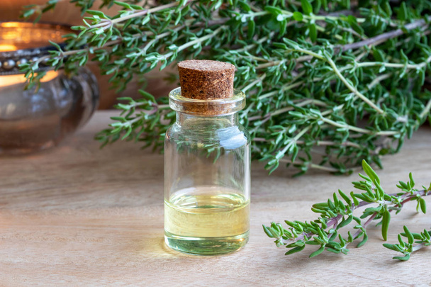 Una bottiglia di olio essenziale con ramoscelli di timo freschi - Foto, immagini