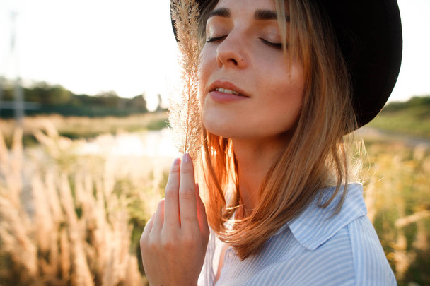 portrait of a beautiful girl in a field with ears at sunset in summer - Foto, imagen