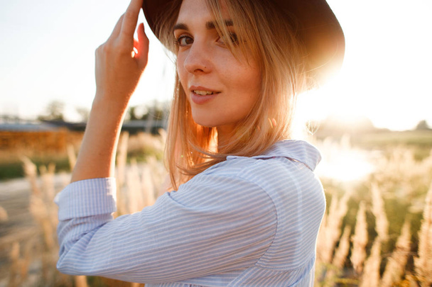 portrait of a beautiful girl in a field with ears at sunset in summer - 写真・画像