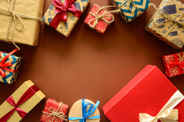 Вид сверху на рождественские подарки, завернутые в подарочную бумагу, украшенную лентой на коричневом бумажном фоне. Концепция новогоднего, праздничного и праздничного оформления. Принято. Плоский лежал
 - Фото, изображение