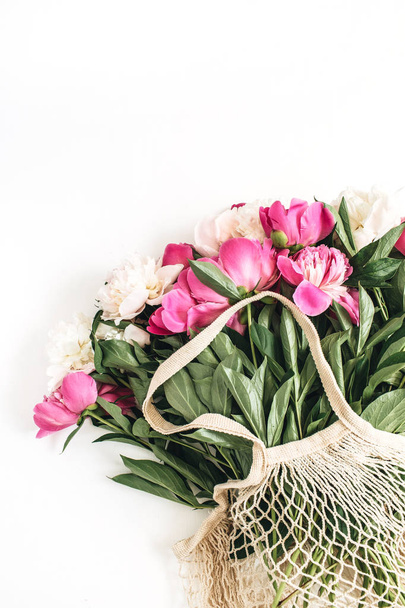 Παιωνία ροζ και λευκά λουλούδια σε κορδόνι τσάντα σε λευκό φόντο. Ελάχιστη έννοια floral επίπεδη lay, κορυφαία προβολή. - Φωτογραφία, εικόνα