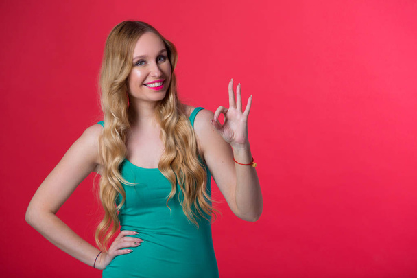 beautiful young girl with flowing hair on red background with hand gesture - Foto, imagen