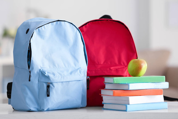 Mochilas escolares com cadernos e maçã na mesa
 - Foto, Imagem