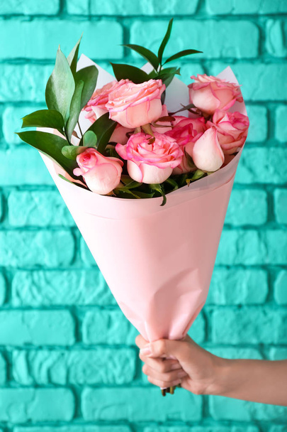 Donna che tiene bouquet di belle rose su sfondo mattone colore
 - Foto, immagini