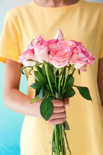 Mujer sosteniendo ramo de hermosas rosas sobre fondo de color, primer plano
 - Foto, Imagen