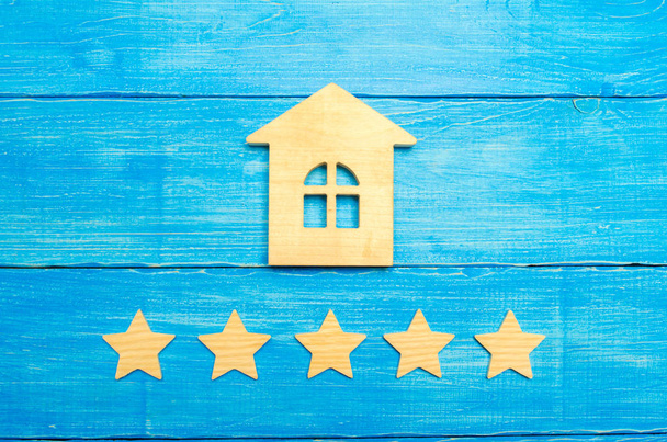 Wooden house and five stars on a gray background. Rating of houses and private property. Buying and selling, renting apartments. The level of the restaurant and hotels. Rating five stars. - Φωτογραφία, εικόνα
