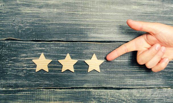 Universal recognition, success and high efficiency. Evaluation of the hotel or restaurant. Application in the market. The hand points to the third star on a dark background. Rating, level of quality. - Φωτογραφία, εικόνα