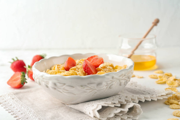 Bowl with healthy cornflakes and strawberry on white table - Фото, изображение