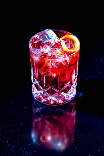 Red cocktail with ice, apparently, of Campari with red grapefruit on a black background. - Фото, изображение