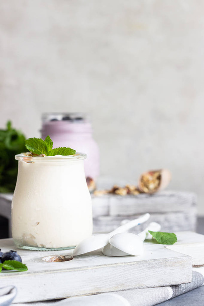 Jars with healthy yogurt with fresh blueberries, granola and mint. Tasty parfaits - Foto, imagen