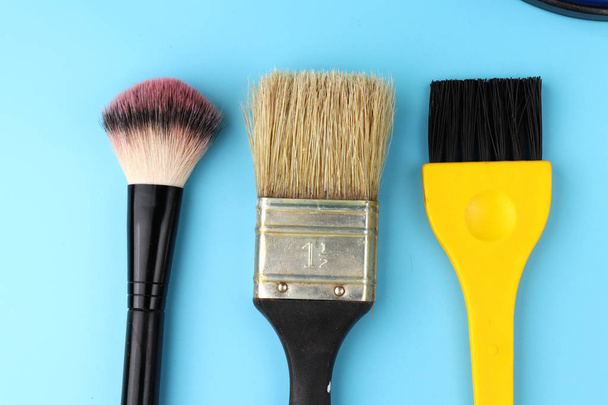 A some cosmetic brushes and one brush for painting walls. Blue background - Photo, Image