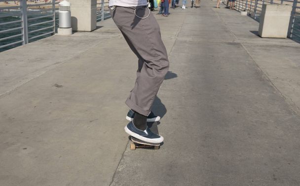 Männliche Skateboarder Schlittschuhe auf der Seebrücke - Foto, Bild