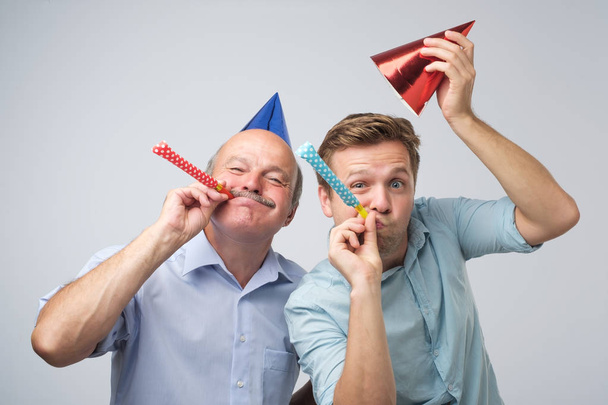 Двое мужчин отец и сын веселятся на дне рождения. Концепция юбилея
 - Фото, изображение