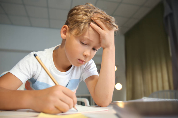 Niño cansado haciendo sus lecciones en casa
 - Foto, Imagen