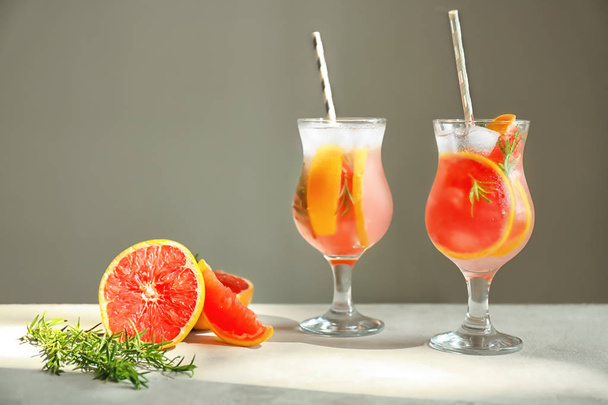 Fresh grapefruit cocktail with rosemary in glasses on light table - 写真・画像